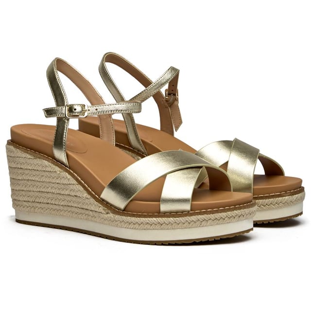 The Cole Haan Silvee transforms the classic espadrille with luxurious gold nubuck and a statement 9cm heel that elevates any summer look. Its rope-edged sole maintains that quintessential Mediterranean charm while the cushioned insole ensures all-day comfort. The secure buckle closure and premium rubber-rope construction make these sandals as practical as they are stunning, perfect for rooftop dinners or seaside strolls.