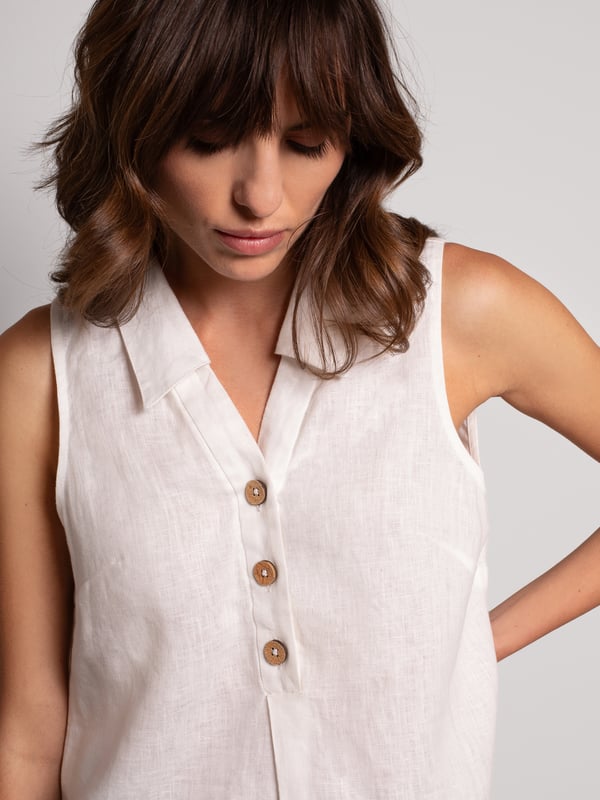This woven sleeveless blouse features a polo collar with a V-neck and buttoned half placket. The box pleat detail at the front of the blouse adds fullness for a body-skimming, flattering silhouette. The coconut buttons and the stepped hem, complete the look. Crafted from crisp yarn-dyed linen, with a unique variegated look to the weave.