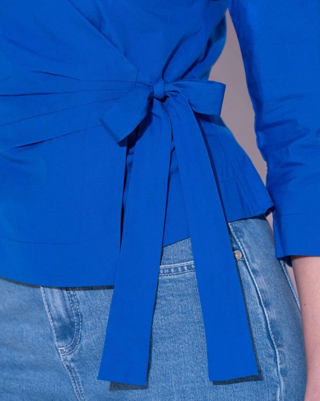 Embrace sophistication with this fitted wrap-style shirt, perfect for day-to-evening occasions. Featuring 3/4 length sleeves, pleated shoulders, cuffs, and adjustable side ties, it offers a flattering silhouette.