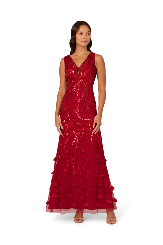 3D flower appliques trail down the skirt of this gorgeous sleeveless maxi dress for a moment of whimsical romance. The floral embellishments finish a bead and sequin design that sparkles and shimmers from the keyhole V-neckline down past the hips. The final effect of the intricate beading is to emphasize the stunning mermaid silhouette of this gown. A back zipper closure ensures the perfect fit. Wear this sumptuous gown to make a grand entrance at your next event.