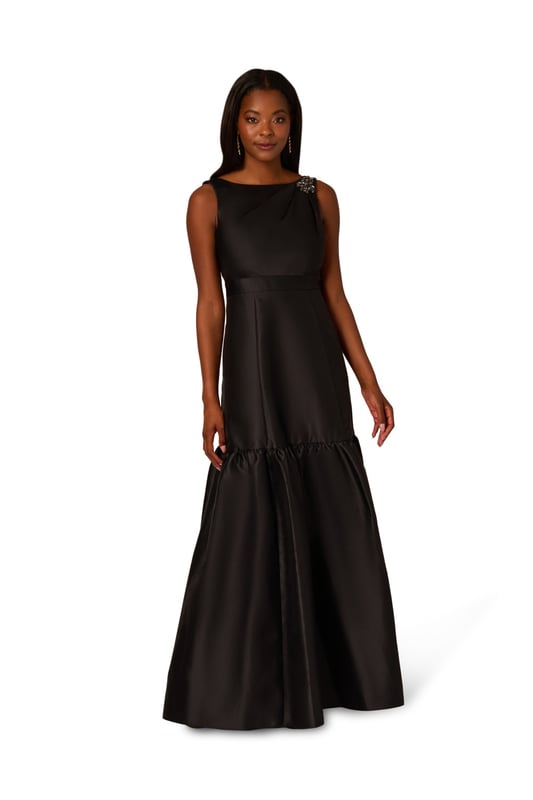 With details this luxurious, you will feel like royalty in this sleeveless ball gown. This formal dress features a sleeveless bodice, boat neckline, and a soft skirt with flounce hem. Designed with shining mikado fabric, this classic evening gown is pleated at the shoulder and accented with stunning stone trim. A hidden zipper closure at the centre back completes this black-tie dress. From charity balls to weddings, this sleeveless mikado gown will shine with a simple clutch and neutral heels.