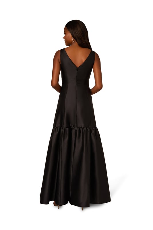 With details this luxurious, you will feel like royalty in this sleeveless ball gown. This formal dress features a sleeveless bodice, boat neckline, and a soft skirt with flounce hem. Designed with shining mikado fabric, this classic evening gown is pleated at the shoulder and accented with stunning stone trim. A hidden zipper closure at the centre back completes this black-tie dress. From charity balls to weddings, this sleeveless mikado gown will shine with a simple clutch and neutral heels.