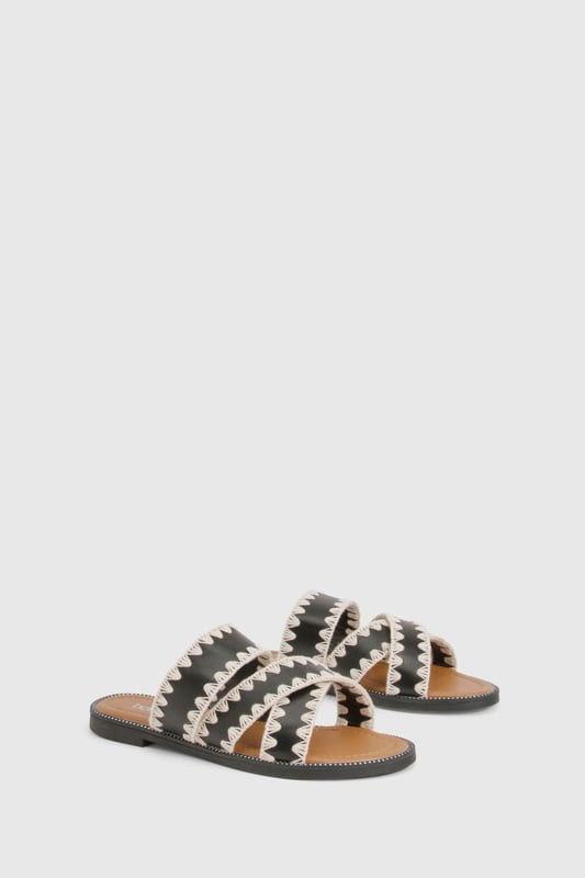 Contrast Blanket Stitch Crossover Sandals Striking contrast cross-over design with distinctive zig-zag stitching detail
Comfortable flat heel measuring between 0-2cm for all-day wear
Open-toe silhouette with dual cross-over straps for a secure fit
Durable PU construction with textured sole for added grip
Slip-on style for effortless wearing and removal
These eye-catching cross-over sandals bring a touch of artisanal flair to your casual wardrobe. The distinctive contrast stitching creates a bold visual statement whilst maintaining a relaxed vibe perfect for summer styling. Pair with cropped linen trousers and an oversized shirt for daytime outings, or team with a flowing maxi dress for garden parties and family gatherings. The flat design ensures comfort for extended wear, making these sandals ideal for city explorations or beachside strolls. Their versatile aesthetic works brilliantly with both neutral and vibrant ensembles, allowing you to customise your look according to the occasion. A statement bangle, as shown on the model, completes the look with a contemporary twist - the perfect finishing touch for these Boohoo sandals that balance style and practicality with effortless charm.