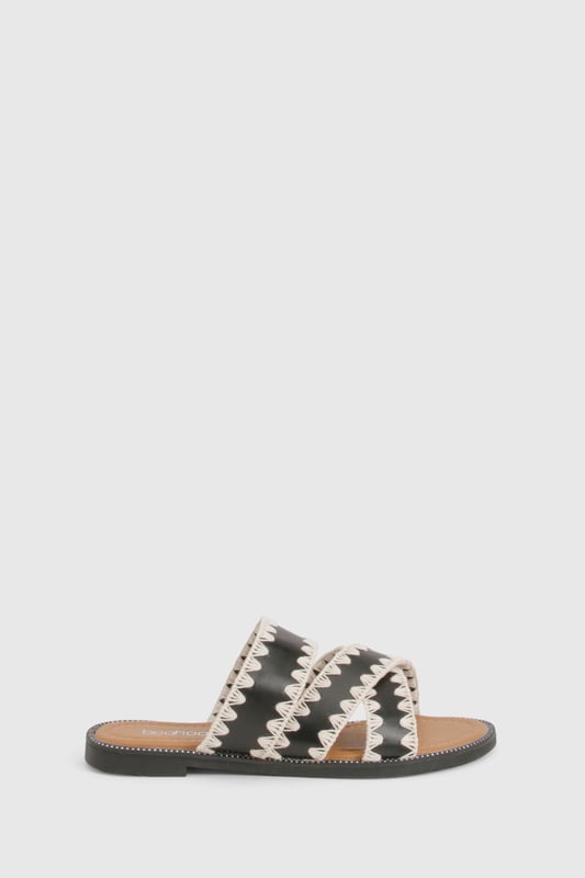 Contrast Blanket Stitch Crossover Sandals Striking contrast cross-over design with distinctive zig-zag stitching detail
Comfortable flat heel measuring between 0-2cm for all-day wear
Open-toe silhouette with dual cross-over straps for a secure fit
Durable PU construction with textured sole for added grip
Slip-on style for effortless wearing and removal
These eye-catching cross-over sandals bring a touch of artisanal flair to your casual wardrobe. The distinctive contrast stitching creates a bold visual statement whilst maintaining a relaxed vibe perfect for summer styling. Pair with cropped linen trousers and an oversized shirt for daytime outings, or team with a flowing maxi dress for garden parties and family gatherings. The flat design ensures comfort for extended wear, making these sandals ideal for city explorations or beachside strolls. Their versatile aesthetic works brilliantly with both neutral and vibrant ensembles, allowing you to customise your look according to the occasion. A statement bangle, as shown on the model, completes the look with a contemporary twist - the perfect finishing touch for these Boohoo sandals that balance style and practicality with effortless charm.