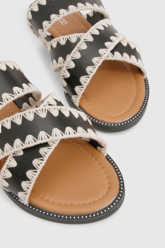 Contrast Blanket Stitch Crossover Sandals Striking contrast cross-over design with distinctive zig-zag stitching detail
Comfortable flat heel measuring between 0-2cm for all-day wear
Open-toe silhouette with dual cross-over straps for a secure fit
Durable PU construction with textured sole for added grip
Slip-on style for effortless wearing and removal
These eye-catching cross-over sandals bring a touch of artisanal flair to your casual wardrobe. The distinctive contrast stitching creates a bold visual statement whilst maintaining a relaxed vibe perfect for summer styling. Pair with cropped linen trousers and an oversized shirt for daytime outings, or team with a flowing maxi dress for garden parties and family gatherings. The flat design ensures comfort for extended wear, making these sandals ideal for city explorations or beachside strolls. Their versatile aesthetic works brilliantly with both neutral and vibrant ensembles, allowing you to customise your look according to the occasion. A statement bangle, as shown on the model, completes the look with a contemporary twist - the perfect finishing touch for these Boohoo sandals that balance style and practicality with effortless charm.