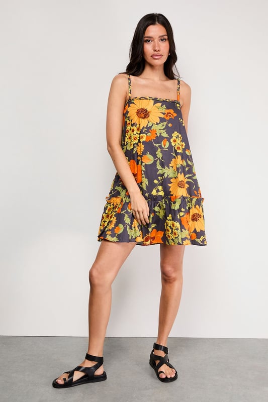 Distinctive plaited straps add a unique textural element to this breezy sundress
        Relaxed A-line silhouette with a feminine flounced hem for added movement
        Square neckline creates a flattering frame for the dcolletage
        Lightweight cotton poplin fabric ensures comfort during warmer days
        Bold floral print makes a confident statement while maintaining versatility
    
    This effortlessly chic sundress captures the essence of carefree summer style with its relaxed silhouette and eye-catching floral pattern. The plaited straps offer a distinctive design element that sets this piece apart, while the flounced hem adds a playful touch to your movement. Style with flat sandals as shown for daytime outings or family gatherings, or dress up with espadrille wedges and statement earrings for garden parties. The cotton poplin fabric ensures breathability during warmer weather, making this an ideal choice for holidays abroad or weekend brunches. Layer with a cropped denim jacket when temperatures cool, or wear over a fitted tee for a contemporary layered look. This versatile sundress transitions seamlessly from casual daytime events to relaxed evening occasions with just a few accessory changes.