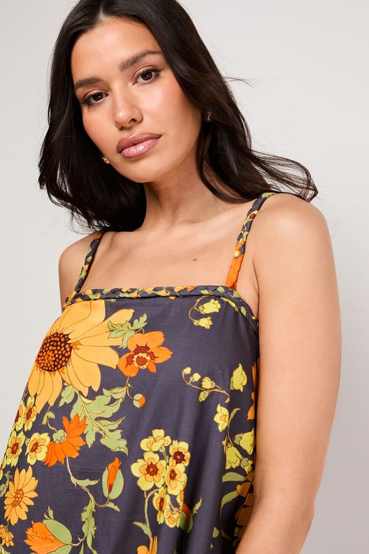 Distinctive plaited straps add a unique textural element to this breezy sundress
        Relaxed A-line silhouette with a feminine flounced hem for added movement
        Square neckline creates a flattering frame for the dcolletage
        Lightweight cotton poplin fabric ensures comfort during warmer days
        Bold floral print makes a confident statement while maintaining versatility
    
    This effortlessly chic sundress captures the essence of carefree summer style with its relaxed silhouette and eye-catching floral pattern. The plaited straps offer a distinctive design element that sets this piece apart, while the flounced hem adds a playful touch to your movement. Style with flat sandals as shown for daytime outings or family gatherings, or dress up with espadrille wedges and statement earrings for garden parties. The cotton poplin fabric ensures breathability during warmer weather, making this an ideal choice for holidays abroad or weekend brunches. Layer with a cropped denim jacket when temperatures cool, or wear over a fitted tee for a contemporary layered look. This versatile sundress transitions seamlessly from casual daytime events to relaxed evening occasions with just a few accessory changes.