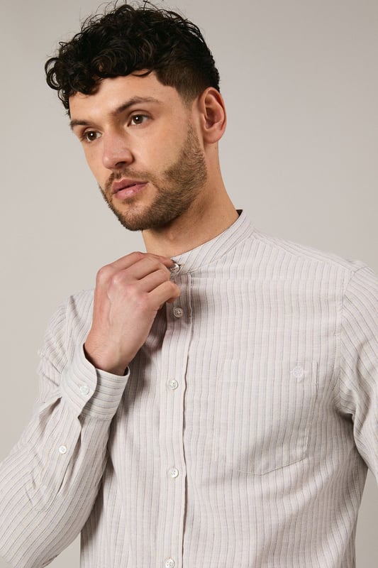 Off White Stripe Grandad Collar Long Sleeve Shirt Distinctive grandad collar design for a contemporary twist on classic shirting
Subtle stripe pattern woven throughout the fabric for understated visual interest
Long sleeves with buttoned cuffs offering versatile styling options
Chest pocket detail adding functional practicality to the design
Relaxed fit with a curved hem perfect for both tucked and untucked styling
This Maine grandad collar shirt combines timeless appeal with modern sensibility. The clean-lined design makes it an effortless addition to your casual wardrobe, whilst the distinctive collar creates a relaxed yet refined aesthetic. Style with dark trousers and loafers as shown for family gatherings or weekend brunches. For a more laid-back approach, pair with chinos and trainers for everyday wear. The versatile nature of this shirt makes it ideal for transitional weather - layer under a lightweight jacket when temperatures drop or wear alone with rolled sleeves during warmer days. The button-through front and woven fabric ensure comfort and ease of movement, making this shirt a practical choice for various casual occasions without compromising on style.