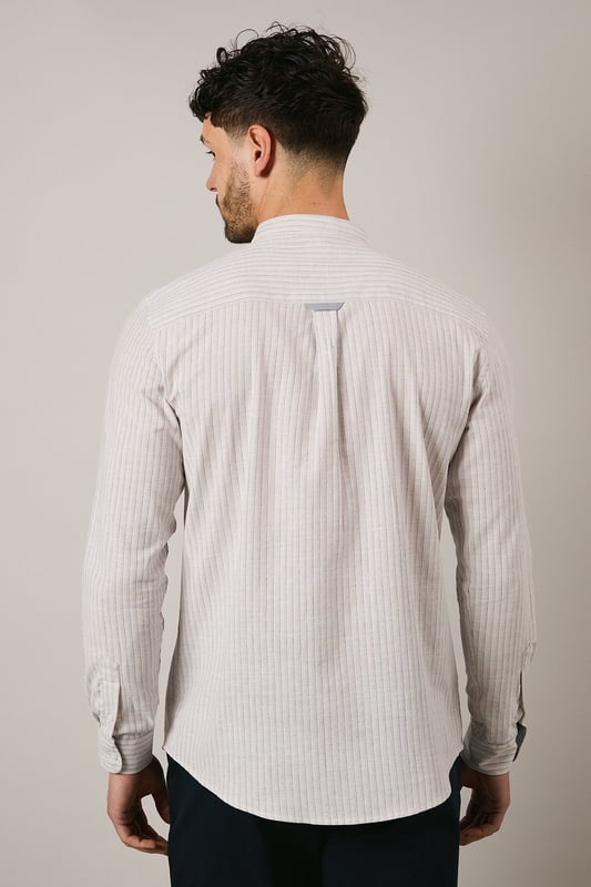 Off White Stripe Grandad Collar Long Sleeve Shirt Distinctive grandad collar design for a contemporary twist on classic shirting
Subtle stripe pattern woven throughout the fabric for understated visual interest
Long sleeves with buttoned cuffs offering versatile styling options
Chest pocket detail adding functional practicality to the design
Relaxed fit with a curved hem perfect for both tucked and untucked styling
This Maine grandad collar shirt combines timeless appeal with modern sensibility. The clean-lined design makes it an effortless addition to your casual wardrobe, whilst the distinctive collar creates a relaxed yet refined aesthetic. Style with dark trousers and loafers as shown for family gatherings or weekend brunches. For a more laid-back approach, pair with chinos and trainers for everyday wear. The versatile nature of this shirt makes it ideal for transitional weather - layer under a lightweight jacket when temperatures drop or wear alone with rolled sleeves during warmer days. The button-through front and woven fabric ensure comfort and ease of movement, making this shirt a practical choice for various casual occasions without compromising on style.