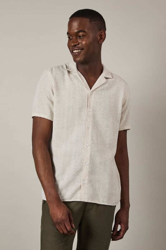 Textured woven fabric adds subtle dimension and visual interest to this casual shirt
        Classic revere collar design creates a relaxed yet refined neckline
        Short sleeves with neat hems perfect for warmer weather
        Button-through front with matching buttons for a clean finish
        Regular fit provides comfortable wear without being overly loose
    
    This Burton textured short sleeve shirt combines casual comfort with understated style. The natural textured fabric offers breathability whilst the revere collar adds a touch of laid-back sophistication that works brilliantly for various casual settings. Style it as shown with chinos or trousers in earthy tones for a balanced look, or pair with your favourite denim for weekend outings. The versatile design makes it ideal for summer barbecues, casual Friday office wear, or meeting mates at the local for a pint. Layer under a lightweight jacket when the temperature drops or wear unbuttoned over a plain t-shirt for a more relaxed approach. This shirt transitions effortlessly from daytime casual to evening gatherings, making it a practical addition to your warm-weather wardrobe that will serve you well for seasons to come.