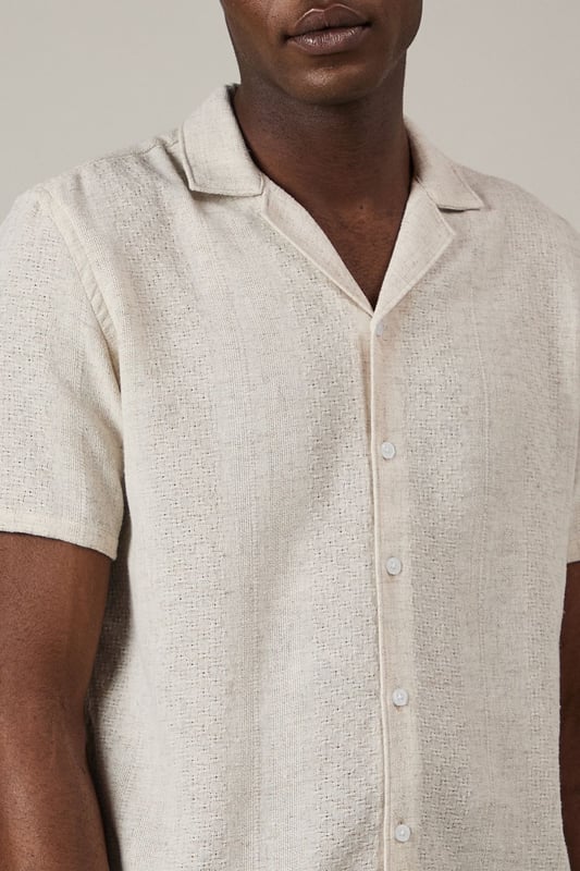 Textured woven fabric adds subtle dimension and visual interest to this casual shirt
        Classic revere collar design creates a relaxed yet refined neckline
        Short sleeves with neat hems perfect for warmer weather
        Button-through front with matching buttons for a clean finish
        Regular fit provides comfortable wear without being overly loose
    
    This Burton textured short sleeve shirt combines casual comfort with understated style. The natural textured fabric offers breathability whilst the revere collar adds a touch of laid-back sophistication that works brilliantly for various casual settings. Style it as shown with chinos or trousers in earthy tones for a balanced look, or pair with your favourite denim for weekend outings. The versatile design makes it ideal for summer barbecues, casual Friday office wear, or meeting mates at the local for a pint. Layer under a lightweight jacket when the temperature drops or wear unbuttoned over a plain t-shirt for a more relaxed approach. This shirt transitions effortlessly from daytime casual to evening gatherings, making it a practical addition to your warm-weather wardrobe that will serve you well for seasons to come.