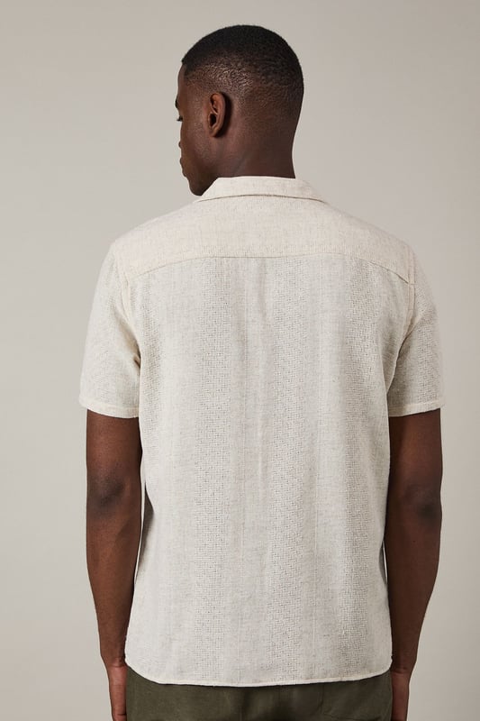 Textured woven fabric adds subtle dimension and visual interest to this casual shirt
        Classic revere collar design creates a relaxed yet refined neckline
        Short sleeves with neat hems perfect for warmer weather
        Button-through front with matching buttons for a clean finish
        Regular fit provides comfortable wear without being overly loose
    
    This Burton textured short sleeve shirt combines casual comfort with understated style. The natural textured fabric offers breathability whilst the revere collar adds a touch of laid-back sophistication that works brilliantly for various casual settings. Style it as shown with chinos or trousers in earthy tones for a balanced look, or pair with your favourite denim for weekend outings. The versatile design makes it ideal for summer barbecues, casual Friday office wear, or meeting mates at the local for a pint. Layer under a lightweight jacket when the temperature drops or wear unbuttoned over a plain t-shirt for a more relaxed approach. This shirt transitions effortlessly from daytime casual to evening gatherings, making it a practical addition to your warm-weather wardrobe that will serve you well for seasons to come.