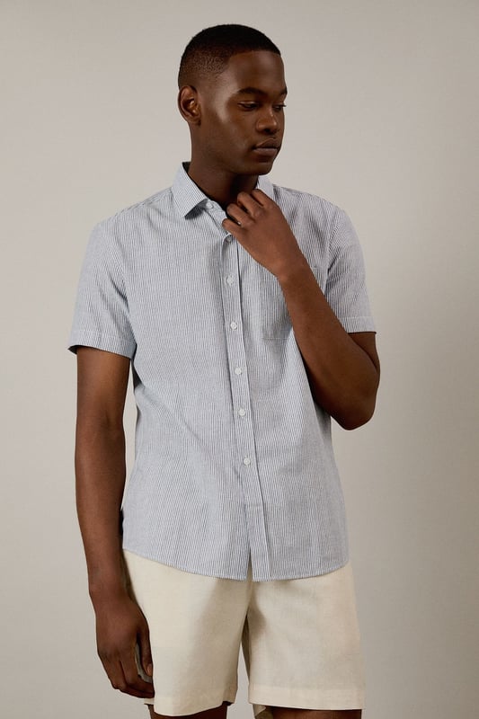 Navy Fine Stripe Short Sleeve Shirt Classic fine stripe pattern for a refined casual look
Short sleeves with neat hems for warm-weather comfort
Traditional collar with structured shape
Convenient chest pocket for added functionality
Regular fit design offering ease of movement throughout the day
This Burton short sleeve shirt combines timeless style with everyday practicality. The fine stripe pattern creates visual interest while maintaining versatility for various occasions. Pair with chino shorts and loafers as shown for a smart casual weekend look perfect for beer garden gatherings or family barbecues. For cooler evenings, layer under a lightweight jumper or team with dark denim jeans and trainers for pub outings with mates. The woven fabric offers breathability and comfort during sporting events or casual match viewings. This shirt transitions effortlessly from daytime casual to evening socialising, making it an essential addition to any practical British wardrobe. A reliable choice for the man who values classic style with contemporary appeal.
