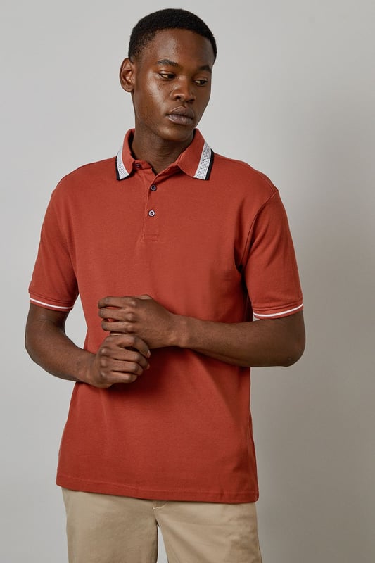 Distinctive jacquard collar with contrasting stripe detail
        Classic button placket with durable buttons for longevity
        Soft cotton fabric for all-day comfort
        Ribbed sleeve cuffs with matching trim for a refined finish
        Regular fit silhouette offering ease of movement
    
    This Burton polo shirt combines timeless style with contemporary detailing, making it a versatile addition to your casual wardrobe. The standout jacquard collar adds character to an otherwise classic design, while the cotton construction ensures breathability and comfort throughout the day. Style it as shown with neutral chinos and white trainers for an effortlessly smart-casual look perfect for weekend pub gatherings or family barbecues. For cooler evenings, layer under a lightweight bomber jacket or casual blazer. The versatile design transitions seamlessly from daytime outings to relaxed evening socials, offering the reliability and understated style that Burton is known for. Machine washable at 30 degrees, this polo maintains its shape and colour with proper care.