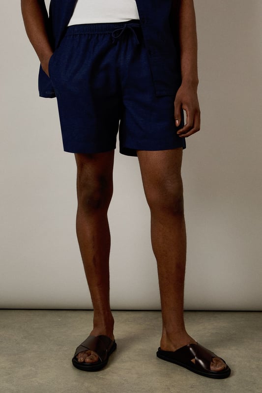 Linen blend fabric offers breathable comfort for warm-weather wear
        Relaxed fit with elasticated waistband for all-day ease
        Side pockets provide practical storage for essentials
        Mid-thigh length creates a flattering silhouette
        Versatile design that pairs effortlessly with both casual and smart-casual attire
    
    These Burton shorts combine comfort and style for the modern man who values both practicality and appearance. The linen blend construction ensures breathability during warmer months whilst maintaining a structured look that works across multiple settings. Style them as shown with a crisp white t-shirt and matching short-sleeved shirt for a coordinated summer ensemble perfect for weekend barbecues or casual pub gatherings with mates. For a more relaxed approach, pair with your favourite graphic tee and trainers for an effortless daytime look. The neutral tone makes these shorts incredibly versatile, allowing them to complement your existing wardrobe with ease. Ideal for family gatherings, sporting events or casual outings, these shorts will quickly become your go-to choice for comfortable yet presentable summer dressing.