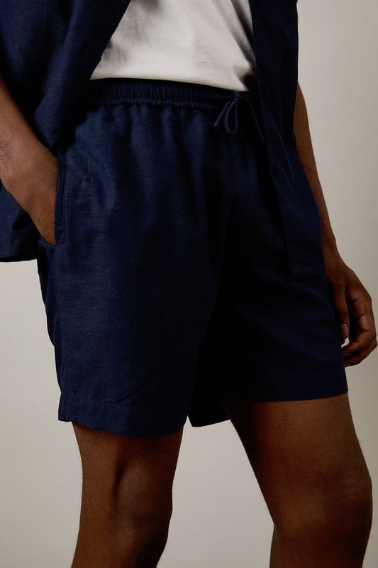 Linen blend fabric offers breathable comfort for warm-weather wear
        Relaxed fit with elasticated waistband for all-day ease
        Side pockets provide practical storage for essentials
        Mid-thigh length creates a flattering silhouette
        Versatile design that pairs effortlessly with both casual and smart-casual attire
    
    These Burton shorts combine comfort and style for the modern man who values both practicality and appearance. The linen blend construction ensures breathability during warmer months whilst maintaining a structured look that works across multiple settings. Style them as shown with a crisp white t-shirt and matching short-sleeved shirt for a coordinated summer ensemble perfect for weekend barbecues or casual pub gatherings with mates. For a more relaxed approach, pair with your favourite graphic tee and trainers for an effortless daytime look. The neutral tone makes these shorts incredibly versatile, allowing them to complement your existing wardrobe with ease. Ideal for family gatherings, sporting events or casual outings, these shorts will quickly become your go-to choice for comfortable yet presentable summer dressing.