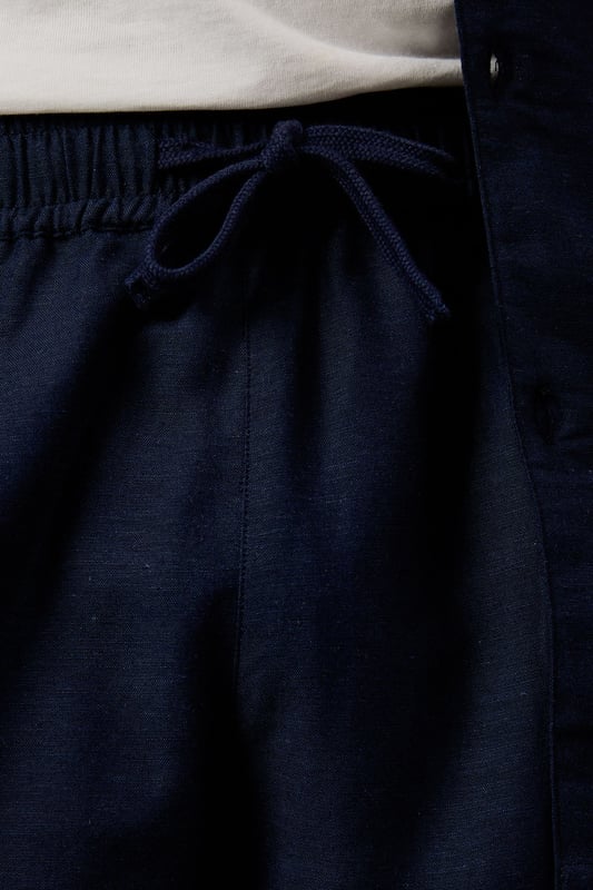 Linen blend fabric offers breathable comfort for warm-weather wear
        Relaxed fit with elasticated waistband for all-day ease
        Side pockets provide practical storage for essentials
        Mid-thigh length creates a flattering silhouette
        Versatile design that pairs effortlessly with both casual and smart-casual attire
    
    These Burton shorts combine comfort and style for the modern man who values both practicality and appearance. The linen blend construction ensures breathability during warmer months whilst maintaining a structured look that works across multiple settings. Style them as shown with a crisp white t-shirt and matching short-sleeved shirt for a coordinated summer ensemble perfect for weekend barbecues or casual pub gatherings with mates. For a more relaxed approach, pair with your favourite graphic tee and trainers for an effortless daytime look. The neutral tone makes these shorts incredibly versatile, allowing them to complement your existing wardrobe with ease. Ideal for family gatherings, sporting events or casual outings, these shorts will quickly become your go-to choice for comfortable yet presentable summer dressing.