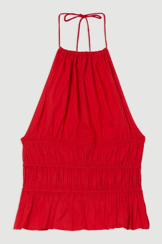Shirred Cotton Tiered Halter Neck Woven Top This Karen Millen woven top combines casual charm with refined detailing, making it a versatile addition to your summer wardrobe. The shirred cotton construction offers both structure and comfort, while the halterneck design creates a feminine neckline that frames the decolletage beautifully. Style with crisp white trousers as shown for a fresh daytime look, or pair with tailored shorts and sandals for weekend brunches. The boxy fit works wonderfully with slim-fitting bottoms to create a balanced silhouette. Add a woven bag and delicate jewellery for family gatherings or casual outings. This piece transitions effortlessly from day to evening; simply swap your flats for block heels and add statement earrings for alfresco dining. Machine washable and easy to care for, this top delivers on both style and practicality. Crafted from pure cotton for breathable comfort throughout the day Distinctive halterneck design with tie fastening at the back for an adjustable fit Intricate shirring detail across the waist creates a flattering silhouette Tiered hem adds movement and dimension to this boxy-fit top Sleeveless style perfect for warmer weather with elegant shoulder-baring appeal