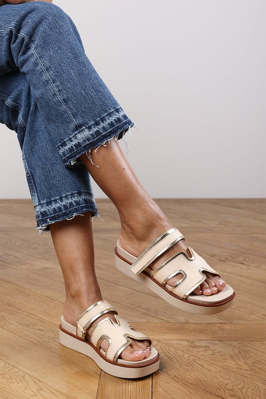 Wheres That From Womens 'Splendor' Slider Flatform Sandals With Cutout Straps Add a touch of glamour to your casual looks with these Splendor Slider Flatform Sandals With Cutout Straps. Featuring textured woven panels and metallic gold trims, they combine comfort and sophistication in one easy slide-on style. The cushioned footbed and elevated sole provide support with a fashionable edge. Perfect for day-to-night wear, holidays, or city strolls. Key Features: • Material: Woven textile and faux leather upper with padded insole • Design: Wide-cut slide with cut-out detailing and gold metallic trim • Closure: Slip-on style for ease and comfort