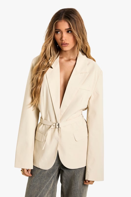 Oversized blazer featuring elegant peak lapels for a sophisticated silhouette
        Distinctive gathered waist detail with tie fastening to create a flattering shape
        Functional front pockets add practicality to this statement piece
        Long sleeves with subtle button detailing at the cuffs
        Versatile woven fabric that maintains structure while offering comfort
    
    Make a bold statement with this contemporary oversized blazer from Boohoo. The gathered waist detail creates a feminine silhouette while maintaining the powerful presence of tailored outerwear. Perfect for formal occasions, pair with tailored trousers and heels for graduations or wedding receptions. For race day elegance, style with a fascinator and a sleek clutch bag. The versatility of this piece also lends itself to more casual styling - as seen on our model with relaxed grey trousers and a headscarf for an effortlessly chic daytime look. The oversized fit offers room for layering over fine knitwear during cooler months, while the tie waist allows you to customise the silhouette to your preference. This blazer bridges the gap between structured formality and contemporary fashion, making it an essential addition to your occasion wardrobe.