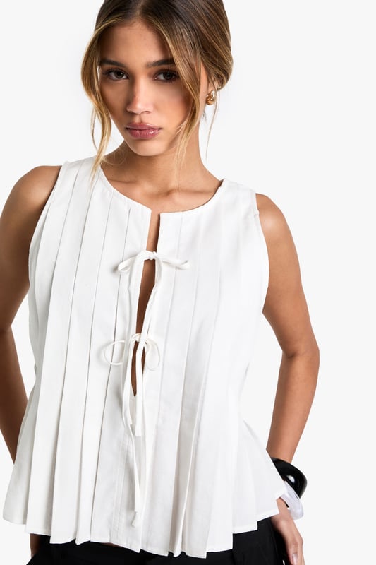 Sleeveless design for warm-weather comfort
        Pleated fabric adds texture and movement
        Tie-front detail for adjustable fit
        Relaxed, flowy silhouette
        Versatile crew neckline
    
    Embrace effortless style with this linen-look top from Boohoo. Perfect for the fashion-forward woman who values both comfort and trend-setting looks, this piece offers a breezy silhouette ideal for warm days. The pleated fabric creates a flattering drape, while the tie-front detail allows for customisable styling. Pair it with wide-leg trousers and sandals for a chic daytime ensemble, or dress it up with a midi skirt and statement earrings for casual evening events. The versatile design makes it a go-to choice for family gatherings, brunch dates, or relaxed outings with friends. Layer it under a denim jacket for cooler evenings, or wear it solo to showcase its unique texture and movement. This top embodies Boohoo's commitment to inclusive, on-trend fashion that doesn't compromise on style or comfort.