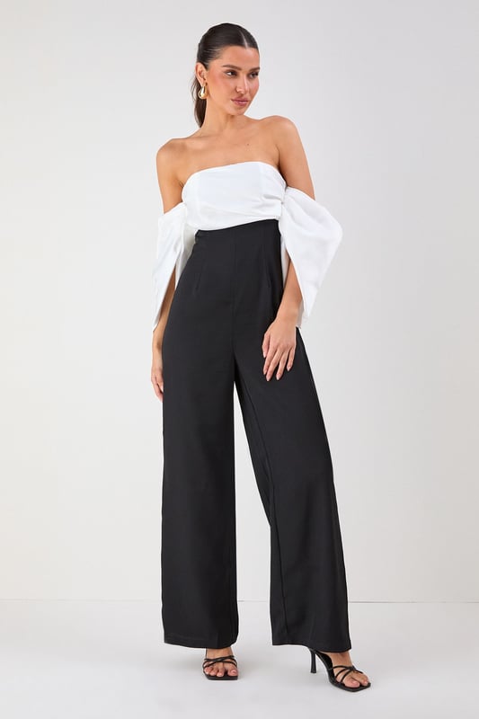 Striking bardot neckline with dramatic volume sleeves for a bold silhouette
        Elegant bandeau bodice with structured design for a flattering fit
        Flowing wide-leg trousers create a sophisticated and elongating effect
        Sleek back design showcases shoulders for a touch of allure
        Versatile jumpsuit perfect for formal occasions and evening events
    
    Make a statement entrance in this show-stopping bardot jumpsuit from Misspap. The dramatic volume sleeves create an architectural silhouette that commands attention, whilst the clean lines of the wide-leg cut offer effortless movement as you glide across the room. Style with strappy heels and statement earrings as seen on our model for maximum impact at summer weddings or cocktail parties. For cooler evenings, drape a tailored blazer over your shoulders without compromising the jumpsuit's striking sleeve detail. The bandeau neckline beautifully frames your dcolletage, making this piece ideal for showcasing a special necklace or simply letting the garment's elegant design speak for itself. A true occasion piece that balances contemporary drama with timeless sophistication.