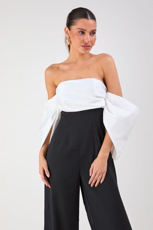 Striking bardot neckline with dramatic volume sleeves for a bold silhouette
        Elegant bandeau bodice with structured design for a flattering fit
        Flowing wide-leg trousers create a sophisticated and elongating effect
        Sleek back design showcases shoulders for a touch of allure
        Versatile jumpsuit perfect for formal occasions and evening events
    
    Make a statement entrance in this show-stopping bardot jumpsuit from Misspap. The dramatic volume sleeves create an architectural silhouette that commands attention, whilst the clean lines of the wide-leg cut offer effortless movement as you glide across the room. Style with strappy heels and statement earrings as seen on our model for maximum impact at summer weddings or cocktail parties. For cooler evenings, drape a tailored blazer over your shoulders without compromising the jumpsuit's striking sleeve detail. The bandeau neckline beautifully frames your dcolletage, making this piece ideal for showcasing a special necklace or simply letting the garment's elegant design speak for itself. A true occasion piece that balances contemporary drama with timeless sophistication.
