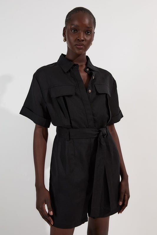 This Karen Millen playsuit combines effortless style with practical design for versatile daywear. The woven viscose linen fabric offers a natural texture and comfortable feel, perfect for warmer days. The belted waist creates a feminine shape while the collared neckline maintains a smart edge. Layer with a lightweight cardigan when the temperature drops, or add a crossbody bag for hands-free convenience during city explorations. This playsuit transitions seamlessly from shopping trips to alfresco dining, making it an essential addition to your warm-weather wardrobe.  Crafted from a viscose linen blend Classic collared neckline with button-through front design Short sleeves with neat cuffs Practical chest pockets Matching fabric belt