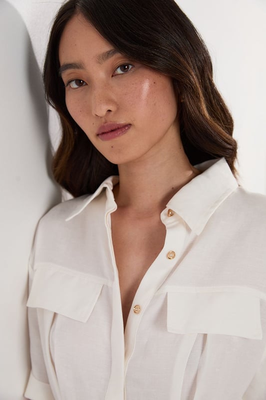 This Karen Millen playsuit combines effortless style with practical design for versatile daywear. The woven viscose linen fabric offers a natural texture and comfortable feel, perfect for warmer days. The belted waist creates a feminine shape while the collared neckline maintains a smart edge. Layer with a lightweight cardigan when the temperature drops, or add a crossbody bag for hands-free convenience during city explorations. This playsuit transitions seamlessly from shopping trips to alfresco dining, making it an essential addition to your warm-weather wardrobe.  Crafted from a viscose linen blend Classic collared neckline with button-through front design Short sleeves with neat cuffs Practical chest pockets Matching fabric belt