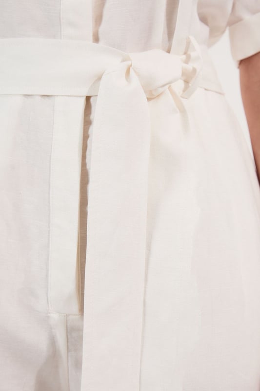 This Karen Millen playsuit combines effortless style with practical design for versatile daywear. The woven viscose linen fabric offers a natural texture and comfortable feel, perfect for warmer days. The belted waist creates a feminine shape while the collared neckline maintains a smart edge. Layer with a lightweight cardigan when the temperature drops, or add a crossbody bag for hands-free convenience during city explorations. This playsuit transitions seamlessly from shopping trips to alfresco dining, making it an essential addition to your warm-weather wardrobe.  Crafted from a viscose linen blend Classic collared neckline with button-through front design Short sleeves with neat cuffs Practical chest pockets Matching fabric belt