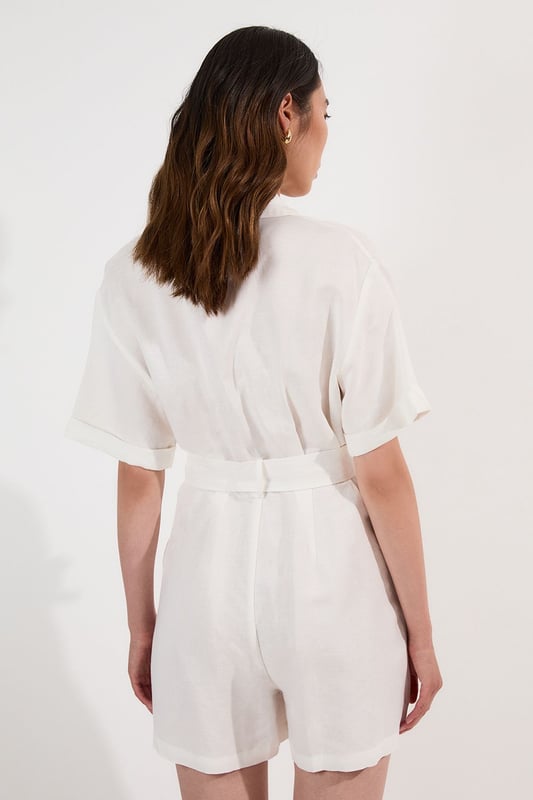 This Karen Millen playsuit combines effortless style with practical design for versatile daywear. The woven viscose linen fabric offers a natural texture and comfortable feel, perfect for warmer days. The belted waist creates a feminine shape while the collared neckline maintains a smart edge. Layer with a lightweight cardigan when the temperature drops, or add a crossbody bag for hands-free convenience during city explorations. This playsuit transitions seamlessly from shopping trips to alfresco dining, making it an essential addition to your warm-weather wardrobe.  Crafted from a viscose linen blend Classic collared neckline with button-through front design Short sleeves with neat cuffs Practical chest pockets Matching fabric belt
