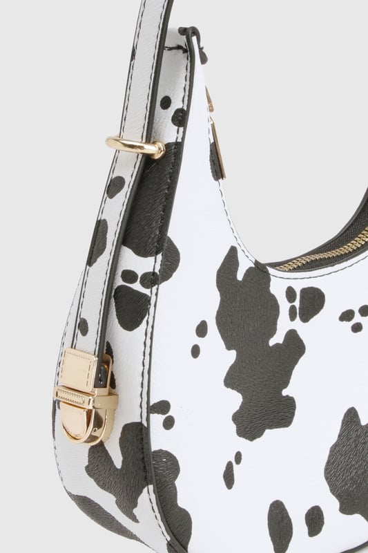 Cow Print Grab Bag Distinctive cow-print design for a bold statement accessory
Compact crescent shape with single shoulder strap
Gold-tone hardware accents for a luxe finish
Secure zip closure to keep essentials safe
Versatile size perfect for nights out
Make a fashion statement with this eye-catching cow-print bag that's sure to turn heads on your next night out. The trendy crescent silhouette sits comfortably under your arm whilst the adjustable shoulder strap offers practical versatility. Pair with a sleek black ensemble as shown for maximum impact, or use it to add a playful touch to any monochrome outfit. The compact yet practical size makes it ideal for carrying your essentials when hitting the club or meeting friends for drinks. The striking pattern works brilliantly against both casual and dressed-up looks - try styling with a little black dress and strappy heels for an evening at the bar, or with jeans and a crop top for a more relaxed approach to urban nightlife. This Boohoo bag delivers the perfect blend of fun and functionality for the fashion-forward partygoer.