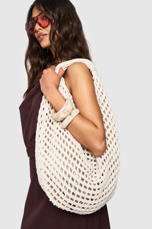 Distinctive crochet design with an open-weave pattern for a bohemian aesthetic
        Spacious interior perfect for carrying daily essentials
        Comfortable shoulder strap with reinforced edges for durability
        Rounded silhouette creates a relaxed, slouchy appearance
        Versatile design that complements both daytime and evening casual outfits
    
    This charming crochet shoulder bag brings a touch of artisanal flair to your everyday ensemble. The intricate open-weave pattern creates a delightful textural contrast against smooth fabrics, making it an eye-catching accessory for the fashion-forward woman. Style with a flowing midi dress and sandals for farmers' markets and seaside strolls, or pair with denim shorts and a simple tee for festival outings. The bag's generous capacity accommodates your phone, wallet, and beauty essentials without compromising on style. For cooler days, this bag works brilliantly with a casual jumper and straight-leg trousers. The neutral tone ensures it will coordinate seamlessly with your existing wardrobe, making it a versatile companion for casual gatherings and weekend brunches throughout the seasons.