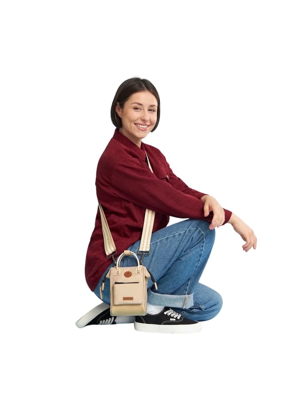 Diese kleine Umhängetasche vereint Funktionalität mit modernem Design. Das aufgenähte Frontlabel setzt einen stilvollen Akzent, während der praktische Reißverschluss das geräumige Hauptfach sicher verschließt. Zwei Innenfächer bieten Platz für wichtige Essentials, darunter Smartphones bis zu einer Höhe von 18 cm. Dank der großen Taschenöffnung ist der Inhalt leicht zugänglich. Der verstellbare, abnehmbare Schultergurt sowie zwei kurze Henkel mit verbindender Lasche ermöglichen vielseitige Tragemöglichkeiten. Gefertigt aus wasserabweisendem und besonders robustem Material, ist die Tasche ein idealer Begleiter für den Alltag. Ein besonderes Highlight ist die auswechselbare Vordertasche 'Nano Bag Fort De Sao Pedro', die mit Gurten und Druckknöpfen sicher befestigt wird. Diese Befestigung sorgt für zusätzlichen Diebstahlschutz. Bitte beachten: Die Schultergurte dieser Umhängetasche sind nicht mit den Gurten der Bauchtaschen kompatibel.