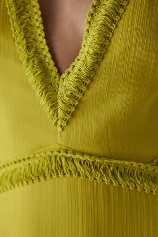 Flowing chiffon maxi dress with delicate fringe trim detailing
        Striking plunge neckline creates a feminine silhouette
        Elegant cut-out back design with tie fastening for adjustable fit
        Tiered skirt construction with gathered waist for added movement
        Fully lined for comfort and opacity while maintaining the lightweight feel
    
    Make a statement in this captivating chiffon maxi dress from Warehouse. The striking plunge neckline frames the dcolletage beautifully, while the cut-out back detail adds an unexpected twist to this flowing piece. The delicate fringe trim and tiered construction create movement with every step, making it perfect for garden parties or summer soires. Style with metallic strappy heels and statement earrings as seen on our model for evening events, or dress down with flat sandals and a woven clutch for daytime gatherings. The lightweight fabric drapes elegantly around the figure, creating a relaxed yet refined silhouette that works wonderfully for warm-weather occasions. This versatile dress transitions effortlessly from casual family gatherings to more formal events with the right accessories.