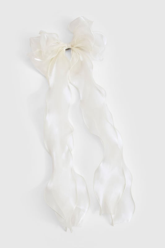 Oversized bow design for a statement look
        Sheer organza fabric creates an ethereal effect
        Long, flowing ribbons for added movement
        Secure metal clip for easy attachment
        Versatile accessory suitable for various hairstyles
    
    Add a touch of whimsy to your ensemble with this enchanting organza hair bow. The oversized design commands attention, while the sheer fabric lends an air of delicate sophistication. Perfect for casual outings or family gatherings, this accessory effortlessly elevates any look. Style it with loose waves for a romantic vibe, or use it to accent a sleek ponytail for a more polished appearance. The long, flowing ribbons create a captivating effect as you move, making it ideal for those who love to make a subtle yet striking impression. Whether you're headed to a picnic in the park or a laid-back brunch with friends, this versatile hair bow is sure to become a go-to piece in your accessory collection.