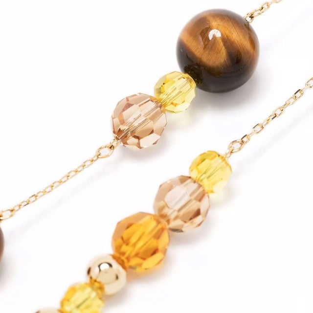 El collar Swarovski Somnia es una pieza de joyería excepcional que combina elegancia elegante y estilo boho chic moderno.\nCon su armoniosa mezcla de ojo de tigre, nácar y cristales en tonos tierra neutros, engastados en una capa de aleación de oro, este collar agregará un brillo especial a cualquier conjunto.\nPerfecto para superponer o como elemento destacado, este collar hace que cada conjunto sea único y radiante.\nJoya con baño de oro y cristales multicolores. Este collar está firmado por la directora creativa Giovanna Engelbert para la Colección II.\n Medidas: Longitud: 47cm\n Composición: Material: Cristales Swarovski, ojo de tigre, capa de aleación de oro.\n Cuidados:\nEvite el contacto con cremas, perfumes y detergentes que puedan dañar el producto. Para mantener el brillo, le recomendamos limpiarlo solo con un paño suave.