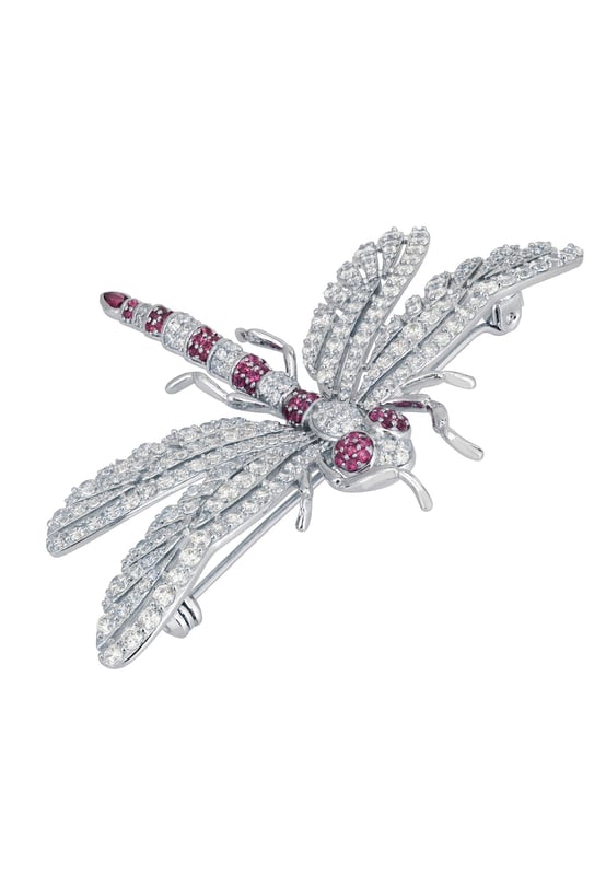 Dragonfly Brooch Silver Ruby Cz The Dragonfly Brooch is a masterfully crafted piece made from high-quality 925 sterling silver. This exquisite brooch captures the delicate beauty of a dragonfly, adorned with a dazzling array of ruby pink and white zirconia. The body of the dragonfly features alternating stripes of pink and white, along with pink eyes, creating a stunning visual contrast that is sure to catch the eye.The wings are intricately designed with a lace-like pattern, encrusted with sparkling white zirconia that shimmer with every movement. The tail of the dragonfly is elegantly finished with a larger ruby-coloured zirconia, making this brooch a true statement piece. Measuring 7.0cm in width, 5.0cm in length, and weighing a comfortable 12.7 grams, this brooch is perfect for adding a touch of glamour to any outfit.Dragonflies hold a special place in jewellery, symbolizing transformation, adaptability, and a deep connection to nature. They remind us to embrace change and live life to the fullest, making this brooch not just a beautiful accessory but a meaningful piece of art.Perfect for nature enthusiasts, lovers of fine craftsmanship, and anyone who appreciates unique and symbolic jewellery. Add the Dragonfly Brooch Silver Ruby Cz to your collection today and let its beauty and symbolism inspire you.