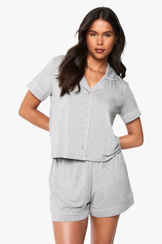 Premium Modal Piping Detail Short Sleeve Shirt & Shorts Pyjama Set Classic button-through shirt with notched collar for a sophisticated nightwear look
Short sleeves with neat cuffed detailing for a polished finish
Relaxed fit shorts with comfortable elasticated waistband
Soft jersey fabric that drapes beautifully for ultimate comfort
Coordinated two-piece set that can be worn together or separately
Embrace bedtime bliss with this chic short-sleeved shirt and shorts set from Boohoo. The traditional shirt styling brings a touch of refinement to your nightwear collection, whilst the relaxed fit ensures maximum comfort for a restful night's sleep. Perfect for warm summer evenings or cosy nights in, this versatile set works brilliantly for lounging about on lazy weekend mornings with a cup of tea and your favourite book. The matching set offers effortless style without compromising on comfort, making it ideal for those impromptu doorstep deliveries or quick dashes to the kitchen. For cooler nights, simply pair with fluffy socks or layer with a lightweight dressing gown. This nightwear essential reflects Boohoo's commitment to creating fashion that's both accessible and on-trend, ensuring you look stylish even when you're winding down.