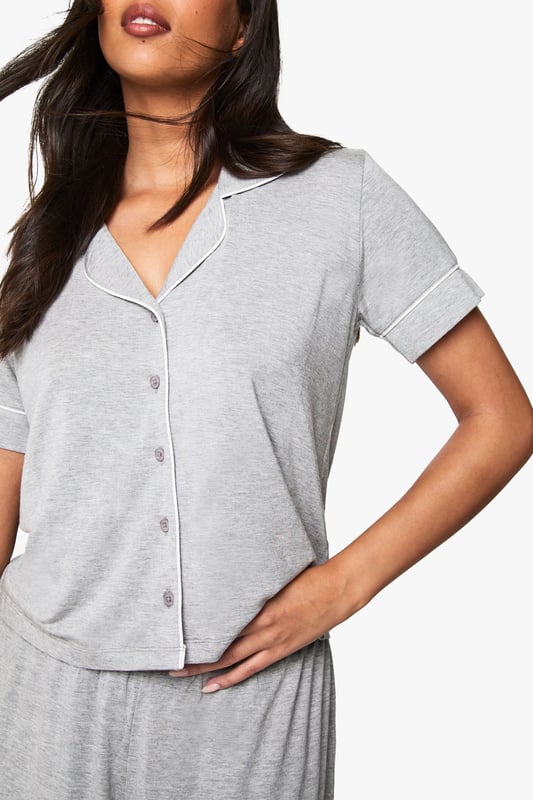 Premium Modal Piping Detail Short Sleeve Shirt & Shorts Pyjama Set Classic button-through shirt with notched collar for a sophisticated nightwear look
Short sleeves with neat cuffed detailing for a polished finish
Relaxed fit shorts with comfortable elasticated waistband
Soft jersey fabric that drapes beautifully for ultimate comfort
Coordinated two-piece set that can be worn together or separately
Embrace bedtime bliss with this chic short-sleeved shirt and shorts set from Boohoo. The traditional shirt styling brings a touch of refinement to your nightwear collection, whilst the relaxed fit ensures maximum comfort for a restful night's sleep. Perfect for warm summer evenings or cosy nights in, this versatile set works brilliantly for lounging about on lazy weekend mornings with a cup of tea and your favourite book. The matching set offers effortless style without compromising on comfort, making it ideal for those impromptu doorstep deliveries or quick dashes to the kitchen. For cooler nights, simply pair with fluffy socks or layer with a lightweight dressing gown. This nightwear essential reflects Boohoo's commitment to creating fashion that's both accessible and on-trend, ensuring you look stylish even when you're winding down.