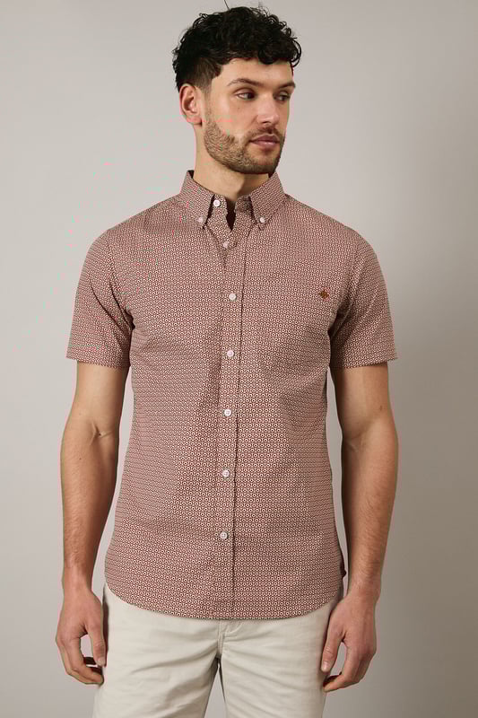 Orange Geo Print Short Sleeve Shirt Distinctive geo print pattern creates visual interest across the entire shirt
Classic button-down collar for a smart-casual finish
Short sleeves with neat hems perfect for warmer weather
Signature Maine embroidered logo detail on chest
Centre back pleat for enhanced comfort and movement
This Maine geo print shirt combines contemporary pattern with timeless design for versatile summer styling. The pure cotton fabric ensures breathability and comfort throughout the day, whilst the structured button-down collar maintains a refined appearance even when worn casually. Style as seen with neutral shorts and white trainers for relaxed weekend brunches or garden gatherings. For evening socials, pair with chinos and loafers for an effortlessly sophisticated look. The subtle geometric pattern works brilliantly with solid-coloured bottoms, allowing the shirt to be the focal point of your ensemble. Perfect for holidays, casual Fridays at the office, or simply elevating your everyday wardrobe with a touch of considered pattern.