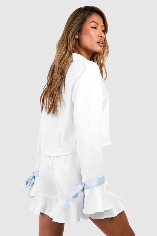 Bridal Something Blue Long Sleeve Shirt & Shorts Pyjama Set Luxurious satin pyjama set for bridal occasions
Chic short-length design for comfort and style
Elegant notched collar and button-front closure
Charming blue bow details on sleeves
Feminine ruffle hem on shorts for a playful touch
Indulge in bridal bliss with this enchanting short pyjama set from Boohoo. Perfect for your special day, this satin ensemble combines comfort with sophistication. The button-front top features a classic notched collar and long sleeves adorned with delightful blue bows, adding a touch of 'something blue' to your bridal attire. The matching shorts boast a flirty ruffle hem, creating a playful silhouette. Ideal for pre-wedding preparations, a relaxing honeymoon morning, or a stylish hen do sleepover. Pair with soft slippers and a silky robe for ultimate lounging luxury, or dress it up with elegant jewellery and a glass of bubbly for those picture-perfect getting-ready moments. This versatile set ensures you'll feel every bit the radiant bride, even in your most intimate moments.