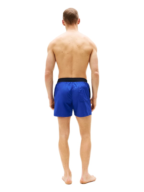 Tommy Hilfiger Schwimmshorts Diese Herren-Badeshorts im Slim Fit überzeugen mit sportlicher Eleganz und passgenauem Sitz. Der oberschenkellange Schnitt betont die Figur und bietet dennoch volle Bewegungsfreiheit. Ein farblich abgesetzter Bund mit Tunnelzug setzt einen frischen Akzent und sorgt für sicheren Halt. Seitliche Eingrifftaschen und eine Gesäßtasche bieten praktische Verstaumöglichkeiten. Der elastische Bund passt sich flexibel an – ideal für aktive Tage am Wasser. Der leichte Stoff trocknet schnell und trägt sich auch nach dem Schwimmen angenehm. Ein dezenter Label-Aufnäher am Bein rundet das Design markant ab. Diese Shorts machen am Strand ebenso eine gute Figur wie auf der Promenade. Schmal geschnitten, aber maximal bequem. Für Männer, die auf Stil auch beim Baden nicht verzichten möchten.