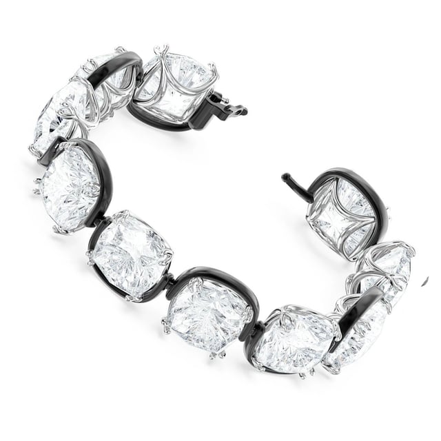 Combining mystery and whimsy, this cuff bracelet creates the illusion of floating stones. It is expertly crafted from a row of oversized cushion-cut clear crystals in an elegant claw setting. Pair it with sleek black evening gloves or a simple long-sleeved T-shirt to elevate your daytime look. Part of the Harmonia family, this bracelet was designed by creative director Giovanna Engelbert for Collection I. How to fasten and open: Place the bar with the rounded end at the widest point of the opposite gap and slide it into the narrower gap. Once in place, pull down the safety clasp at the top to secure the closure. To open, lift the safety clasp and slide the bar into the wider gap to release.\n Measures: Length (minimum - maximum): 16.5 - 22.7 cm\n Width: 1.7 cm\n Composition: Material: Crystals, Various metallic finishes\n Care:\nAvoid contact with creams, perfumes and detergents that may damage the product. To maintain its shine, we recommend cleaning it only with a soft cloth.