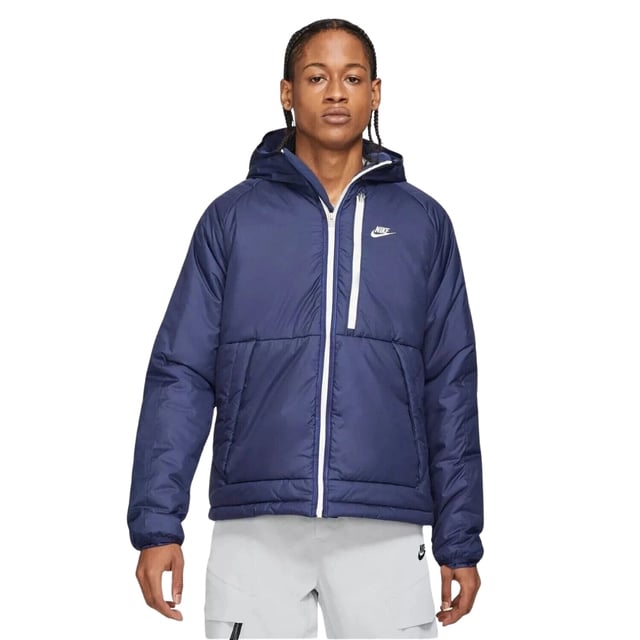 Stay warm and dry with the Nike Dark Blue Padded Jacket, crafted from 100% polyester with Therma-FIT technology to retain heat efficiently. This water-repellent jacket features a full zip fastening for easy wear, two front pockets secured with buttons, and a zippered left breast pocket for secure storage. The attached hood offers extra protection against the elements, while the iconic Nike badge on the left breast adds a stylish touch. Perfect for outdoor activities or casual wear, this jacket combines functionality and comfort in a sleek design