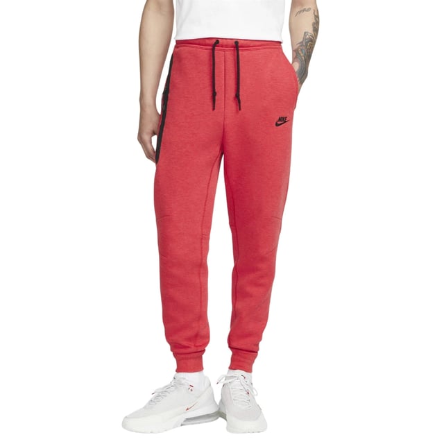 Nike - Schwarze Jogginghose Mit Verschweißten Reißverschlüssen Und Rot Erleben Sie Komfort und Style mit der Nike Black Taped Zips Red Sweatpants. Sie besteht aus einem weichen Materialmix aus 53 % Baumwolle und 47 % Polyester für Strapazierfähigkeit und Atmungsaktivität. Der elastische Bund und die Bündchen sowie der Kordelzug sorgen für einen sicheren, verstellbaren Sitz. Die Slim-Fit-Jogginghose mit schmal zulaufendem Bein und regulärer Länge bietet eine moderne Silhouette. Zu den praktischen Details gehören zwei Fronttaschen, eine davon mit Reißverschluss zur sicheren Aufbewahrung wichtiger Utensilien, und das ikonische Nike Swoosh-Logo auf der linken Hüfte verleiht ihr einen sportlichen Touch. Diese Jogginghose ist perfekt für Freizeit und Training und vereint Funktionalität mit elegantem Design