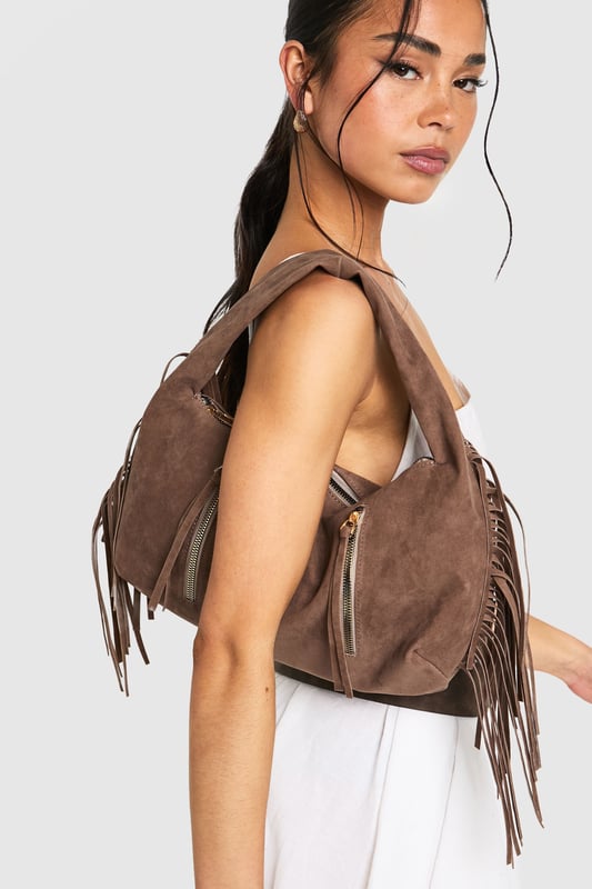 Faux suede hobo bag with statement fringe detailing along both sides
        Spacious main compartment with secure zip closure
        Twin decorative front zips with metallic pull tabs
        Comfortable curved top handle for easy carrying
        Soft-touch finish that mimics the luxurious feel of genuine suede
    
    This boho-inspired faux suede bag brings a touch of festival chic to your everyday wardrobe. The distinctive fringe detailing creates movement and texture, whilst the practical hobo silhouette offers ample space for your essentials. Style with white wide-leg trousers and a fitted top as shown for a balanced daytime look, or pair with a floaty midi dress and ankle boots for evening drinks. The versatile design transitions effortlessly from office to dinner date, making it the perfect companion for your busy social calendar. The curved handle sits comfortably on your shoulder, whilst the secure zip closure keeps your belongings safe. This Boohoo bag combines practicality with on-trend styling, perfect for the fashion-forward woman who values both form and function.