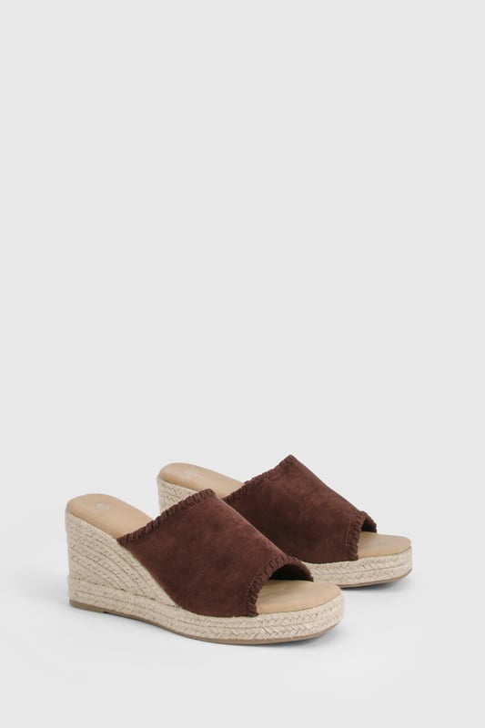 Chic suede mule espadrilles with comfortable mid-height wedge heel (5-6.5cm)
        Open toe design perfect for showcasing summer pedicures
        Traditional rope-wrapped wedge sole for authentic Mediterranean appeal
        Slip-on style for effortless wear and convenience
        Cushioned footbed providing all-day comfort and support
    
    These versatile Wildleder Espadrilles from Boohoo blend timeless Mediterranean charm with contemporary styling. The classic rope-wrapped wedge creates a flattering silhouette whilst maintaining walkable comfort with its mid-height design. Perfect for casual daytime events, these mules pair beautifully with flowing midi skirts and summer dresses as shown, or style with cropped trousers and a linen blouse for relaxed weekend brunches. The suede finish adds a touch of luxury to your everyday wardrobe, whilst the open-toe silhouette keeps your look fresh and seasonal. Complement with natural accessories like the woven handbag featured for a coordinated summer ensemble. These espadrilles transition effortlessly from family gatherings to beachside restaurants, offering both style and practicality for the fashion-forward woman who values versatility in her footwear collection.
