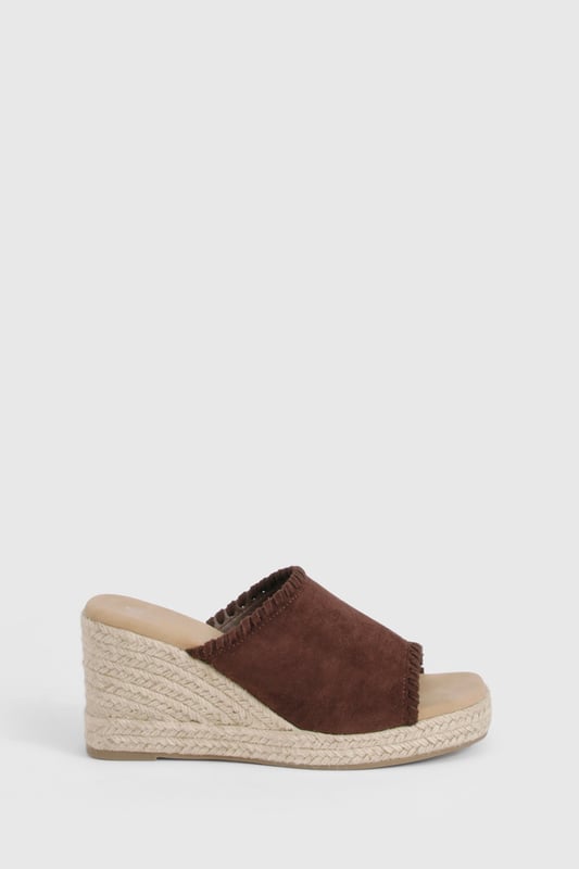 Chic suede mule espadrilles with comfortable mid-height wedge heel (5-6.5cm)
        Open toe design perfect for showcasing summer pedicures
        Traditional rope-wrapped wedge sole for authentic Mediterranean appeal
        Slip-on style for effortless wear and convenience
        Cushioned footbed providing all-day comfort and support
    
    These versatile Wildleder Espadrilles from Boohoo blend timeless Mediterranean charm with contemporary styling. The classic rope-wrapped wedge creates a flattering silhouette whilst maintaining walkable comfort with its mid-height design. Perfect for casual daytime events, these mules pair beautifully with flowing midi skirts and summer dresses as shown, or style with cropped trousers and a linen blouse for relaxed weekend brunches. The suede finish adds a touch of luxury to your everyday wardrobe, whilst the open-toe silhouette keeps your look fresh and seasonal. Complement with natural accessories like the woven handbag featured for a coordinated summer ensemble. These espadrilles transition effortlessly from family gatherings to beachside restaurants, offering both style and practicality for the fashion-forward woman who values versatility in her footwear collection.