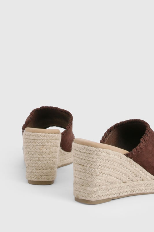 Chic suede mule espadrilles with comfortable mid-height wedge heel (5-6.5cm)
        Open toe design perfect for showcasing summer pedicures
        Traditional rope-wrapped wedge sole for authentic Mediterranean appeal
        Slip-on style for effortless wear and convenience
        Cushioned footbed providing all-day comfort and support
    
    These versatile Wildleder Espadrilles from Boohoo blend timeless Mediterranean charm with contemporary styling. The classic rope-wrapped wedge creates a flattering silhouette whilst maintaining walkable comfort with its mid-height design. Perfect for casual daytime events, these mules pair beautifully with flowing midi skirts and summer dresses as shown, or style with cropped trousers and a linen blouse for relaxed weekend brunches. The suede finish adds a touch of luxury to your everyday wardrobe, whilst the open-toe silhouette keeps your look fresh and seasonal. Complement with natural accessories like the woven handbag featured for a coordinated summer ensemble. These espadrilles transition effortlessly from family gatherings to beachside restaurants, offering both style and practicality for the fashion-forward woman who values versatility in her footwear collection.